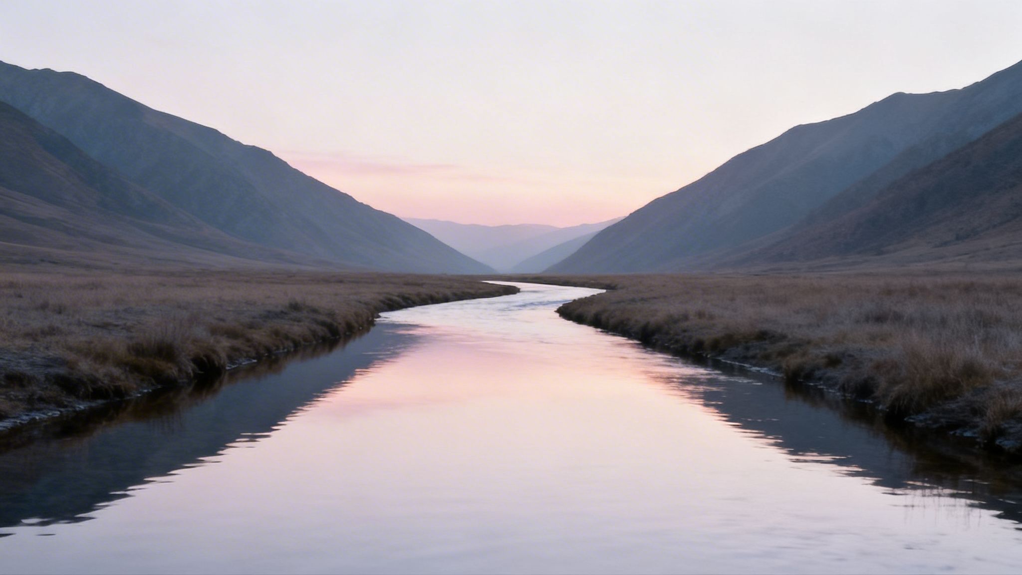A serene river winds through a vast valley with mountains under a soft pink and purple sunset sky.