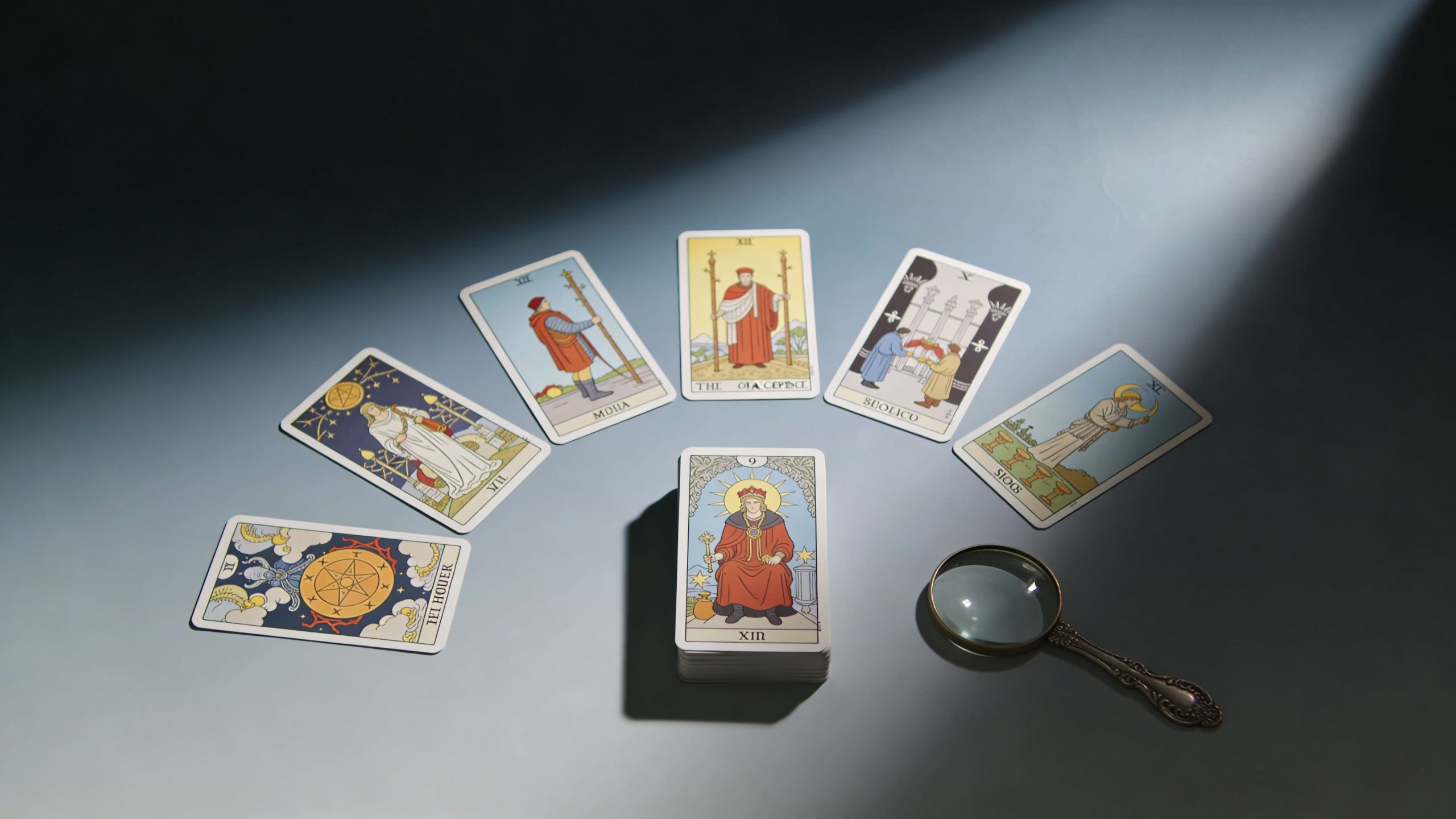 A tarot card reading setup featuring a spread of cards and a magnifying glass on a table.